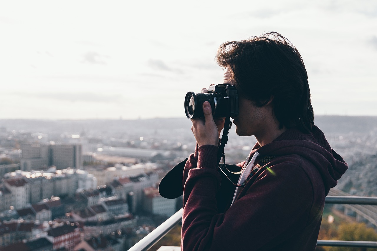 Darstellung eines Fotografens, vor einer urbanen Kulisse. 